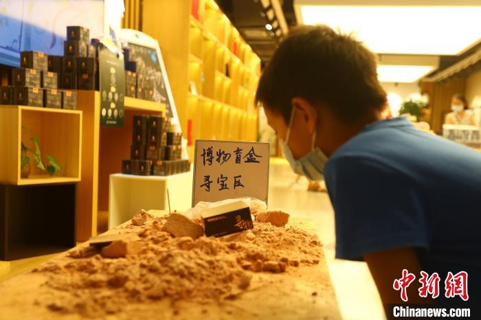 圖為在江西省博物館天工坊，一名小男孩端詳著已經(jīng)拆解完畢的“考古盲盒”現(xiàn)場?！⒄祭?攝